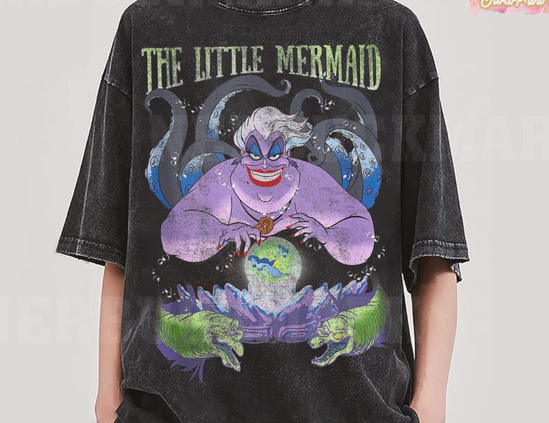 May include: Black t-shirt featuring a graphic of Ursula from The Little Mermaid. The design includes Ursula, tentacles, and the text "THE LITTLE MERMAID". The artwork is in shades of purple, green, and blue.