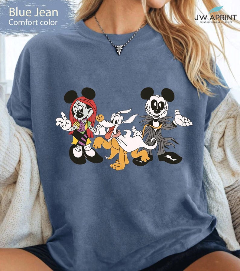 Puede incluir: Camiseta azul vaquero de color c&oacute;modo con un gr&aacute;fico de personajes de dibujos animados. El dise&ntilde;o incluye a Minnie Mouse, Pluto y Jack Skellington. La camiseta es de color azul liso.