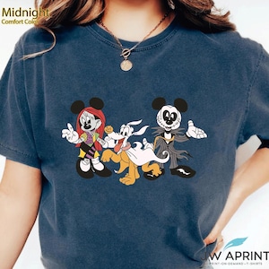 Puede incluir: Camiseta azul medianoche con un gr&aacute;fico de Halloween de Mickey Mouse, Sally, Pluto y Jack Skellington. La camiseta tiene el texto "JW APRINT" en la parte inferior. La camiseta est&aacute; hecha de material Comfort Color.