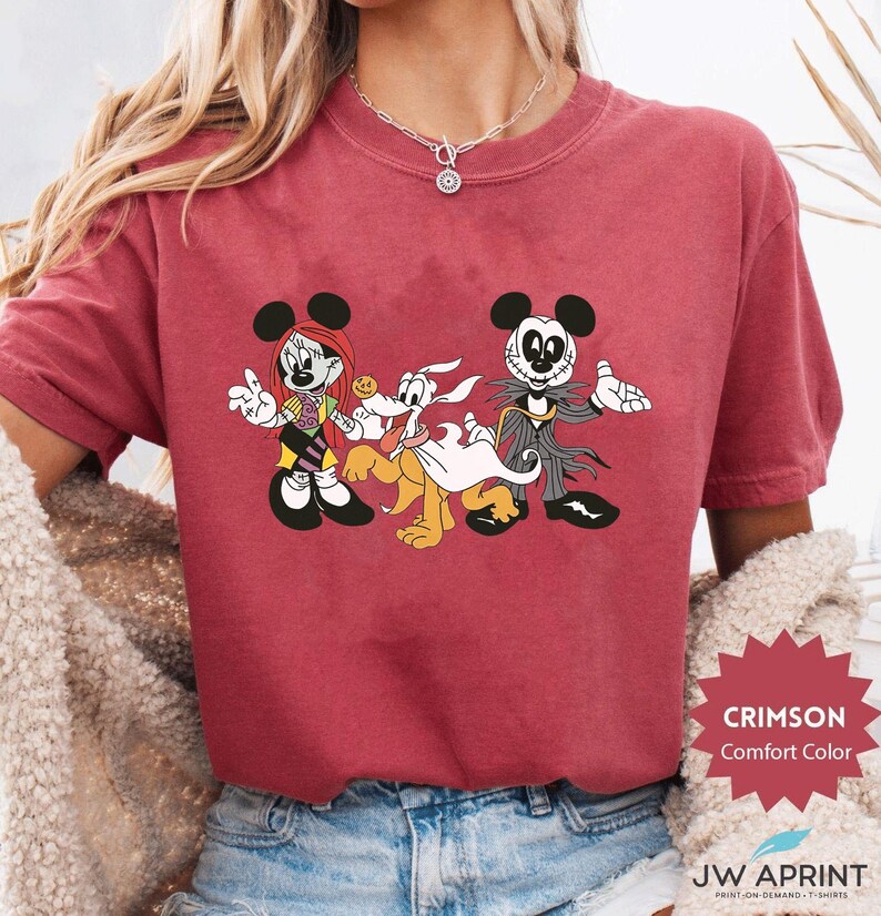 Puede incluir: Camiseta Crimson Comfort Color con un dibujo animado de Minnie Mouse, Pluto y Jack Skellington con tem&aacute;tica de Halloween. La camiseta tiene el texto "CRIMSON Comfort Color" y "JW APRINT" impreso.