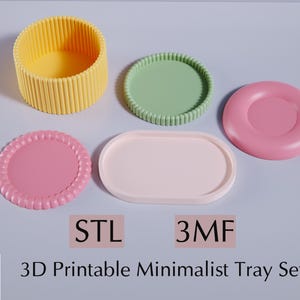 May include: A set of four 3D printable minimalist trays in pink, green, and yellow. The trays are designed to be used as decorative organizers or serving trays. The image includes the text "STL 3MF 3D Printable Minimalist Tray Set".