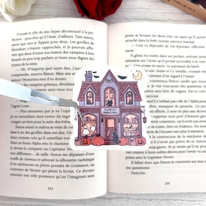Peut inclure: Un autocollant fantaisiste représentant une maison hantée violette avec l'inscription "HAUNTED BOOKSTORE". Le design comprend des citrouilles, des fantômes et un croissant de lune, parfait pour Halloween.