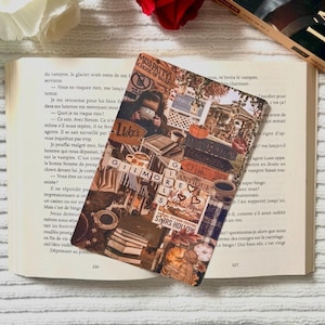 May include: A bookmark with a collage design, featuring images and text associated with Stars Hollow. The bookmark includes coffee cups, books, and the words "Gilmore Girls" and "Luke's". It is placed on an open book, with a red rose in the background.