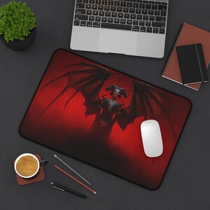 May include: A red and black mousepad with a graphic of a winged demon with horns and a red background.