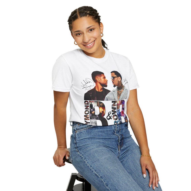 K&ouml;nnte beinhalten: Wei&szlig;es T-Shirt mit einer Grafik von zwei M&auml;nnern, Unterschriften und dem Text "Raymond & Brown". Die Person tr&auml;gt eine blaue Jeans. Das Design enth&auml;lt die W&ouml;rter "Raymond" und "Brown" in einer stilisierten Schriftart.