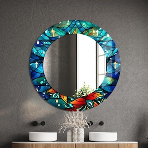 May include: A round mirror with a blue, green, and orange stained glass design. The mirror is hanging on a gray wall above a wooden vanity with two sinks.