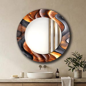 May include: A circular decorative mirror with an abstract design. The frame has a pattern of brown, black, and grey curved shapes. The mirror is mounted on a light-coloured wall above a wooden vanity unit.