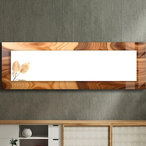 May include: A rectangular wall mirror featuring a wide frame with a glossy, swirling wood grain pattern in shades of brown and tan. The mirror surface is clear and rectangular, with a small, delicate illustration of light brown leaves in the corner.