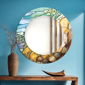 May include: A round mirror with a stained glass design featuring a seashell and ocean wave pattern in shades of blue, green, and yellow. The mirror is hanging on a blue wall above a wooden console table.
