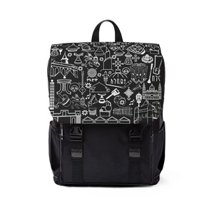 May include: Black and white backpack with a flap closure and two front pockets. The top flap features a repeating pattern of line drawings of buildings, musical instruments, and other cultural symbols. The backpack has a top handle and adjustable shoulder straps.