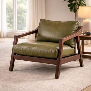 May include: A modern armchair with a dark wood frame and olive green leather cushions. The chair has a low profile with a square seat and back, and angled armrests. The chair is placed on a neutral-colored rug.