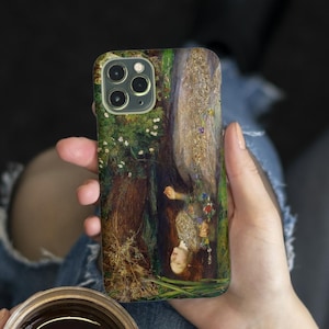 Puede incluir: Funda de teléfono con una pintura de una mujer en un entorno forestal. La obra de arte representa a una mujer con cabello rojo, vestida con un vestido blanco, rodeada de árboles y flores. La funda tiene un acabado brillante y un recorte para la cámara.