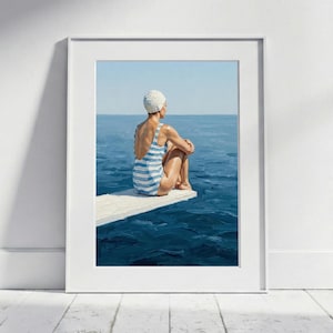 Op de afbeelding: Een ingelijst schilderij toont een persoon in een blauw-wit gestreept badpak en badmuts, zittend op een wit duikplank, kijkend naar een uitgestrekte blauwe oceaan onder een heldere hemel. Het kunstwerk roept een gevoel van rust en ontspanning op.