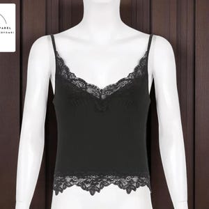 May include: Black camisole top with delicate lace trim along the neckline and hem. The top has thin spaghetti straps and a V-neck design. The minimalist apparel brand logo is in the top left corner.