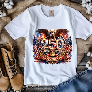 May include: White t-shirt featuring a colorful graphic celebrating a 250th anniversary. The design includes an eagle, American flags, fireworks, and the years 1776 and 2026. The word "ANNIVERSARY" is displayed on a red banner.