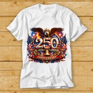 May include: White t-shirt featuring a patriotic design. The graphic includes an eagle, the number 250, American flags, and the text "1776-2026 Anniversary". The design incorporates red, white, blue, and gold colors.