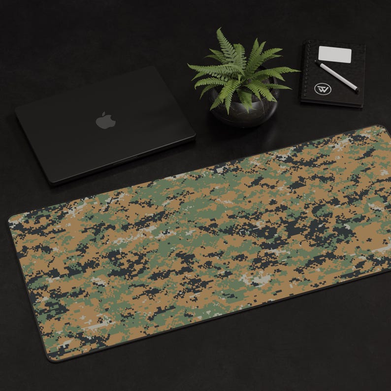 K&ouml;nnte beinhalten: Eine gro&szlig;e, rechteckige Mausmatte mit einem digitalen Tarnmuster in Gr&uuml;n-, Braun- und Beiget&ouml;nen. Die Mausmatte liegt auf einer schwarzen Oberfl&auml;che.