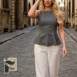 May include: A sleeveless gray top with a peplum design paired with cream-colored wide-leg pants. The top has a boat neck and a fitted silhouette. The pants are high-waisted and made of a lightweight fabric. The image also includes a logo that says "Flair by Bel".