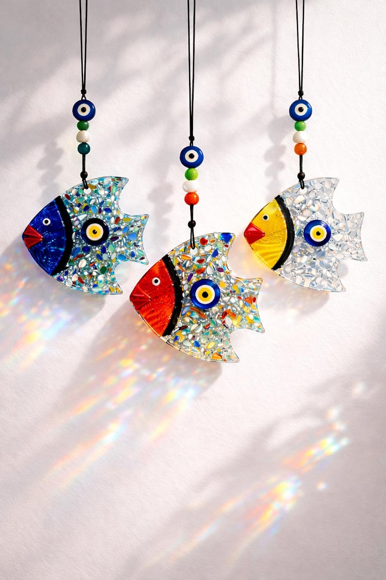 Pu&ograve; includere: Tre ornamenti decorativi a forma di pesce con motivi a mosaico. Ogni pesce presenta una diversa combinazione di colori: blu, rosso e giallo. Sono decorati con un occhio turco e appesi a cordoncini neri, adatti per l'arredamento della casa.