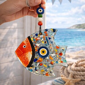 Detailed shot of the textured fused glass surface on the colorful fish suncatcher. The translucent blue and amber glass pieces shimmer when placed near a bright window or light source.