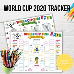 May include: Two printed World Cup 2026 tracker sheets featuring a group stage tracker and a knock-out games bracket. The designs include colorful bunting, a cartoon soccer ball character, and a trophy illustration. A cup of colored pencils is included.