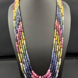 Puede incluir: Collar multicadena hecho de cuentas de piedras preciosas de colores. El collar presenta una variedad de colores, incluyendo azul, verde, amarillo, rosa y rojo. Las cuentas son todas redondas y tienen un acabado liso y pulido.