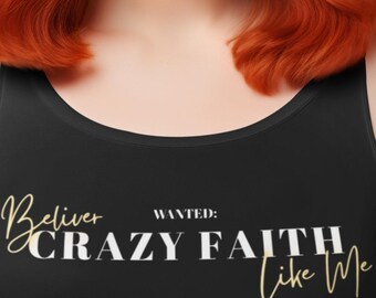 May include: A woman with red hair and a pink bow wearing a black tank top with the text "Believe, Wanted: Crazy Faith Like Me" in gold lettering. She is also wearing a pink skirt.