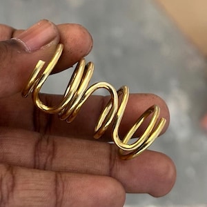 May include: A gold-colored metal spring, coiled into a spiral shape.