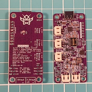 Puede incluir: Dos placas de circuito p&uacute;rpura con intrincados componentes electr&oacute;nicos. Una placa presenta texto que incluye "Switch Guide", "Li-ion Battery" y "Backup Battery". La otra placa tiene un logotipo de b&uacute;ho estilizado y especificaciones de voltaje y corriente.
