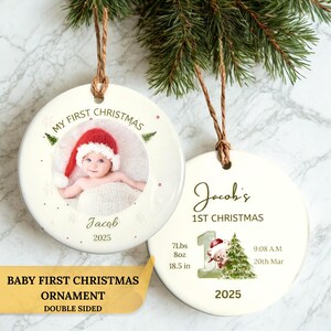 Puede incluir: Dos adornos redondos de cerámica blanca con cordel marrón. Uno muestra la foto de un bebé con gorro de Papá Noel, el texto 'MY FIRST CHRISTMAS', 'Jacob' y '2025'. El otro muestra 'Jacob's 1ST CHRISTMAS', '7Lbs 8oz', '18.5 in', '9:08 A.M', '20th Mar', '2025' y una pequeña ilustración de un oso junto a un árbol.
