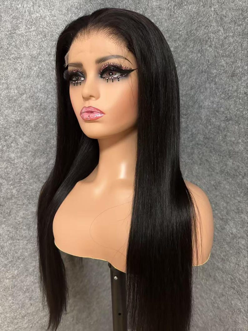 May include: A long, straight black wig with a lace front. The wig is styled in a sleek, straight style and is worn on a mannequin head.