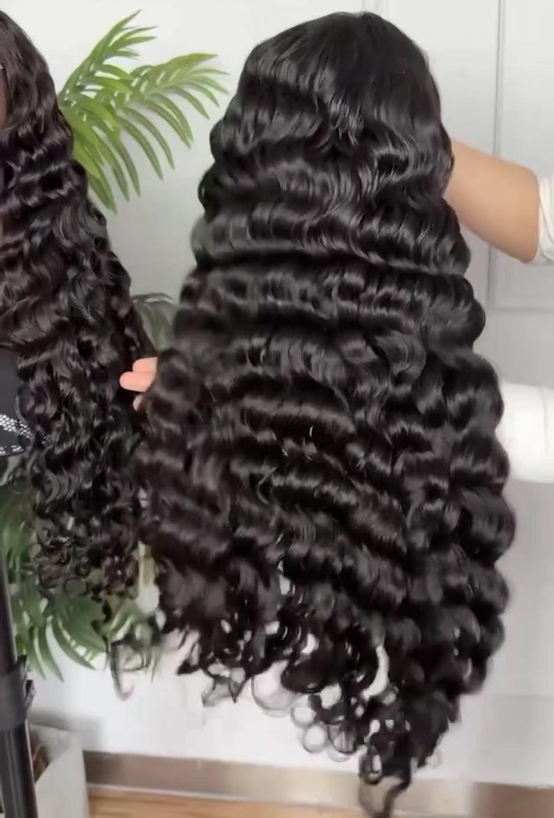 May include: A long, black, wavy wig with a deep wave pattern. The wig is styled with voluminous curls and appears to be made of synthetic or human hair. The hair is a rich, dark color and has a natural-looking sheen. The wig is likely designed for fashion or cosplay.