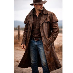 May include: A long, distressed brown leather duster coat with a wide collar and button-front closure, worn over a dark brown button-down shirt, blue denim jeans with a brown leather belt, and a brown wide-brimmed hat.