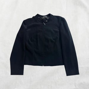Peut inclure: Une veste noire zipp&eacute;e avec un col montant.