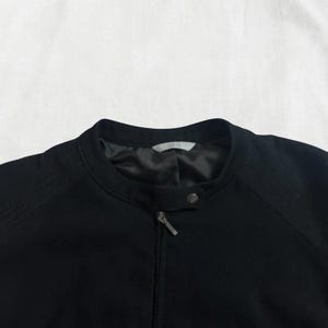 Peut inclure: Une veste noire zipp&eacute;e avec un col montant.
