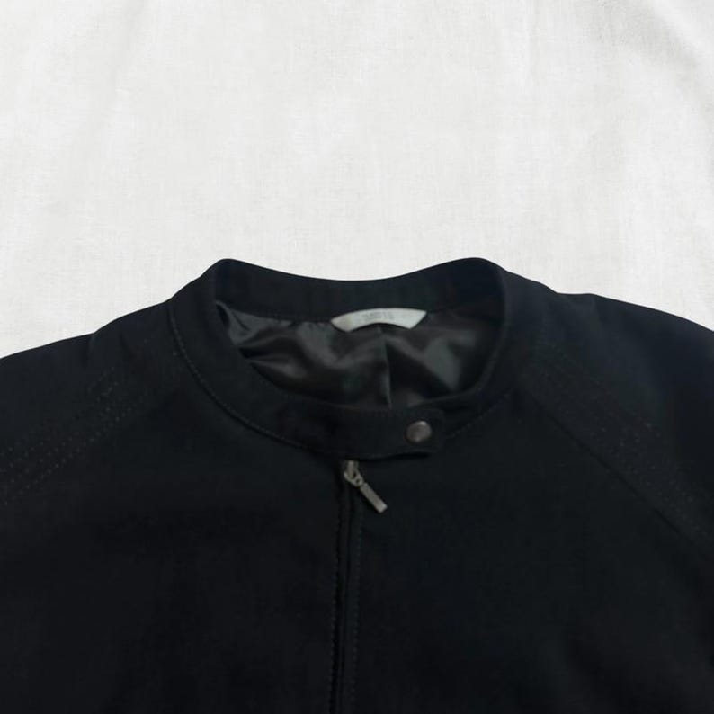 Peut inclure: Une veste noire zipp&eacute;e avec un col montant.