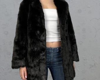 May include: A black faux fur coat with a long, slightly flared silhouette. The coat has a collar and a button closure.