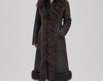 May include: A long, dark brown coat featuring a thick, textured fur trim along the front opening and the hemline. The coat has long sleeves, a smooth matte finish on the main body, and reaches below the knees, paired with black leather boots.