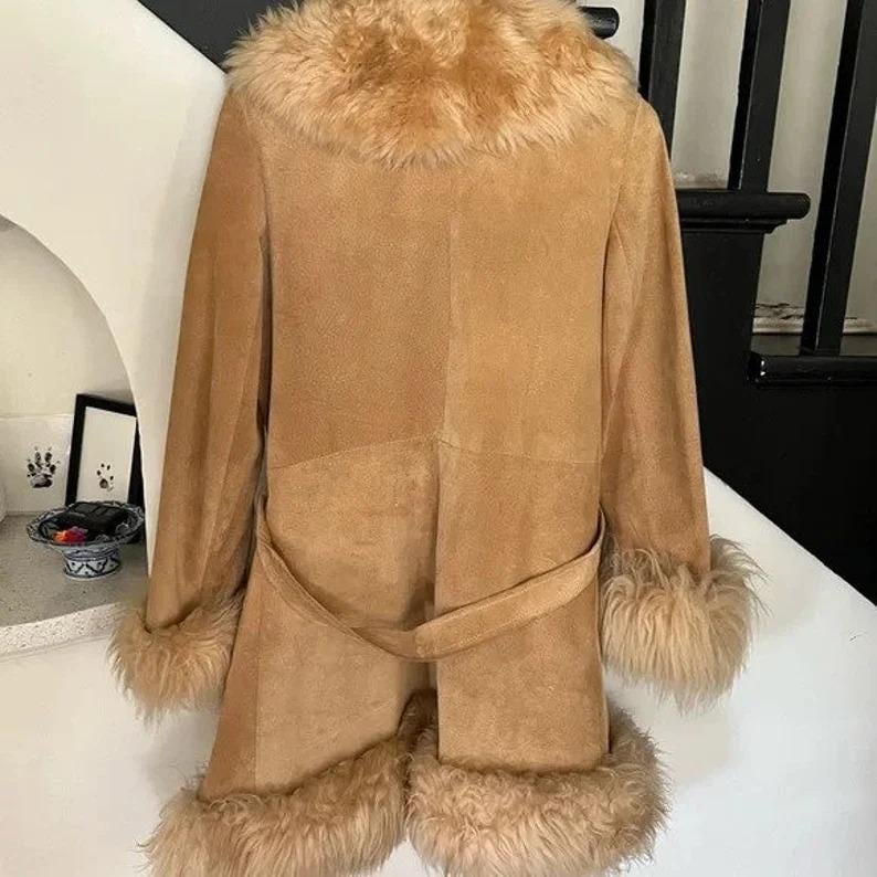 May include: A tan suede coat with a faux fur collar, cuffs, and hem. The coat features a matching belt and a classic, longline silhouette. The fur trim adds a touch of luxury to this vintage-inspired outerwear.