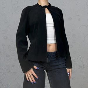 Peut inclure: Un blazer noir ajust&eacute; avec un col montant et une fermeture &agrave; bouton unique. Le blazer a une taille cintr&eacute;e et des manches longues.