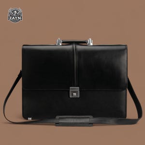 May include: A black leather briefcase with silver hardware and a shoulder strap. The briefcase has a top handle and a lock.