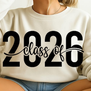 May include: Cream-colored sweatshirt with the text "2026 class of" in a bold black font. The word "class" is in a cursive script. The sweatshirt is a casual style, suitable for graduation celebrations.