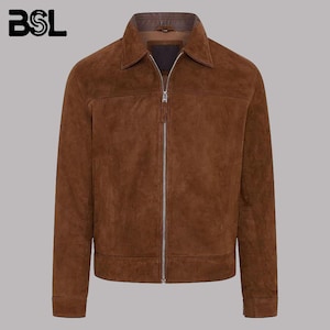 Könnte beinhalten: Eine braune Wildlederjacke mit klassischem Kragen, einem durchgehenden silberfarbenen Metallreißverschluss, langen Ärmeln mit geknöpften Manschetten und einem geraden Saum. Das Innenfutter des Kragens besteht aus dunkelbraunem Leder.