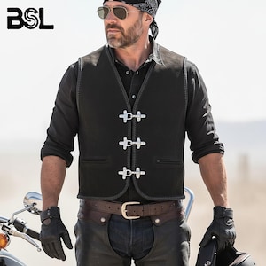 Op de afbeelding: Zwart leren vest met drie zilveren sluitingen, gedragen over een zwart overhemd. Het vest heeft een klassieke biker-stijl. De afbeelding toont ook een bruine leren riem, zwarte handschoenen en een zwarte bandana.