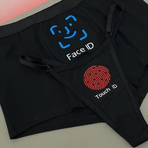 May include: Black underwear set featuring a blue Face ID graphic with a facial recognition icon and a red Touch ID graphic with a fingerprint icon. The design includes a pair of boxer briefs and a thong with adjustable straps, displaying the text Face ID and Touch ID clearly on the fabric.