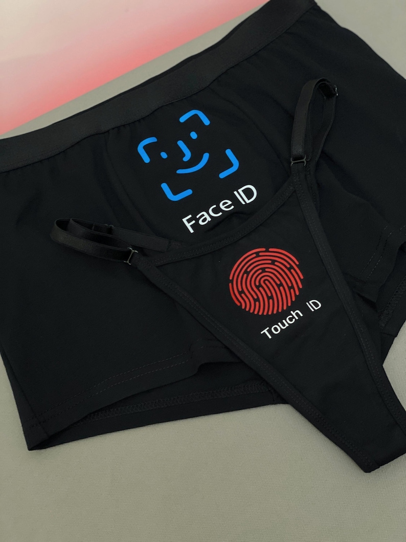 May include: Black underwear set featuring a blue Face ID graphic with a facial recognition icon and a red Touch ID graphic with a fingerprint icon. The design includes a pair of boxer briefs and a thong with adjustable straps, displaying the text Face ID and Touch ID clearly on the fabric.