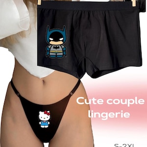 Può includere: Boxer neri con grafica a fumetto di Batman e perizoma nero con grafica di Hello Kitty. È visibile anche il testo "Cute couple lingerie" e "S-2XL high quality".