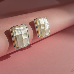 Può includere: Un paio di orecchini d'argento con intarsi in madreperla bianca. Gli intarsi sono a scacchiera.
