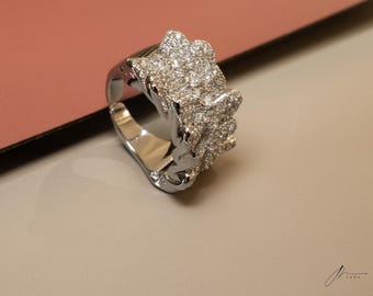 May include: A silver ring with a large, intricate design featuring a cluster of sparkling white stones.