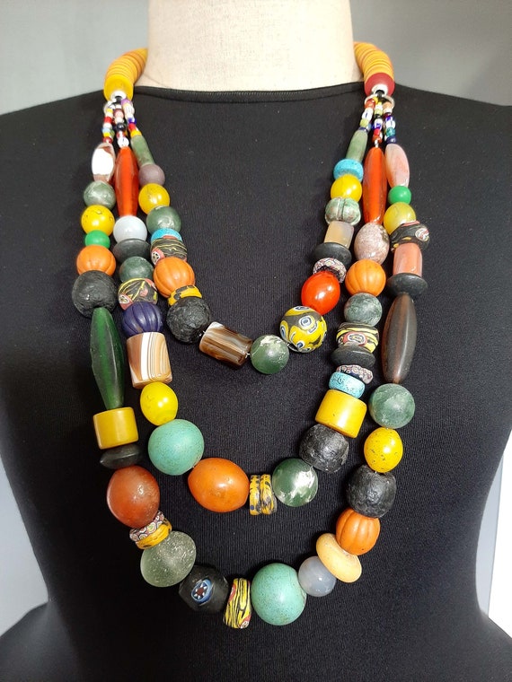A West African Three Strand Necklace Of Black Coconut Discs, White Shells,  And Copal Amber Beads